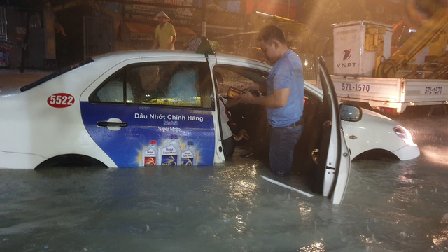  Một đoàn khách di chuyển trên taxi phải xuống xe lội bộ vì nước ngập hết nửa xe không thể di chuyển. 